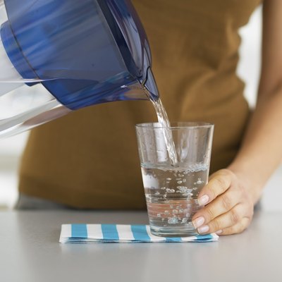 Closeup on housewife pouring water into glass