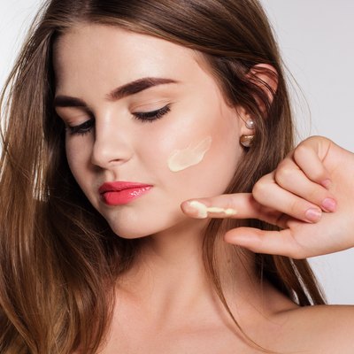 Girl is applying facial cream to cheek
