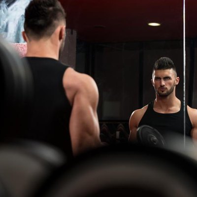 Man In The Gym Exercising Biceps With Dumbbells