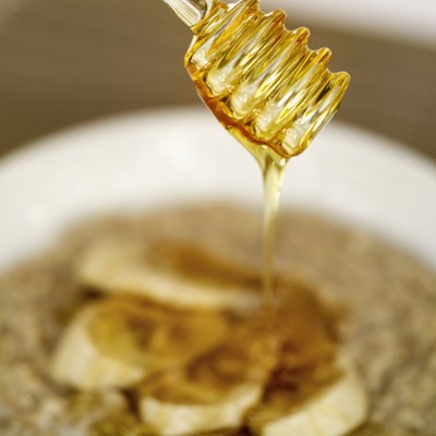 close-up of a honey dipper over a bowl of cereal