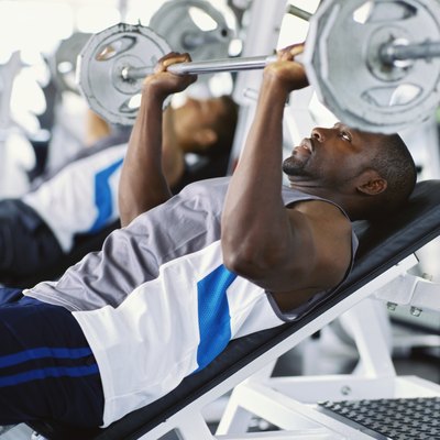 Two mid adult men exercising in a gym with weights