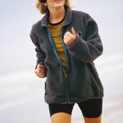 Woman running along beach, wearing headphones