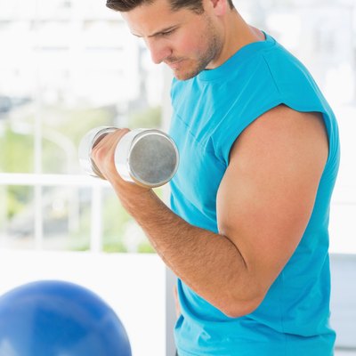 Sporty young man with dumbbell in gym