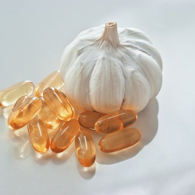 garlic oil capsules on a white reflective surface