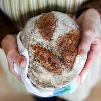 Whole-grain artisan bread loaf in grandmother hands, baking