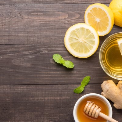 Cup of ginger tea with lemon and honey on table.