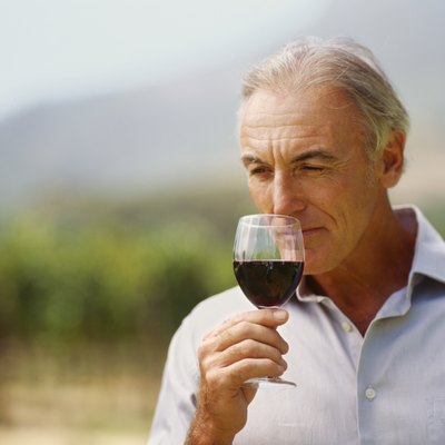 close-up of a mature man sniffing a glass of red wine