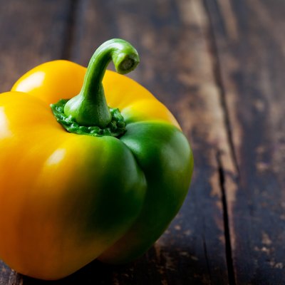 Yellow green pepper on wood