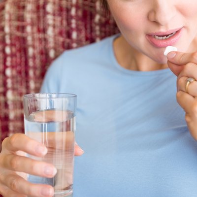 Pregnant woman taking a vitamin tablet