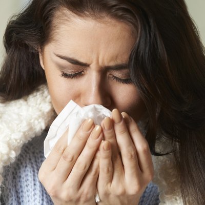 Woman With Cold Holding Tissue And Sneezing