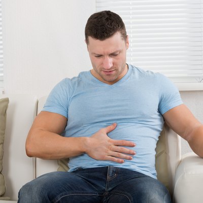 Man With Stomach Ache Sitting On Couch At Home