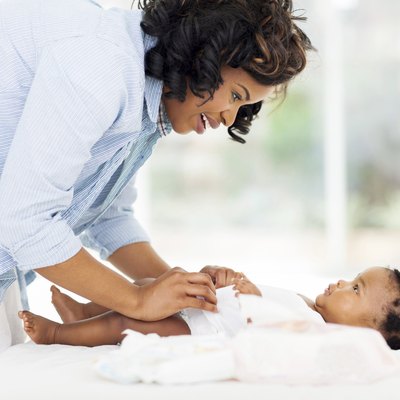 african american mother changing baby's diaper
