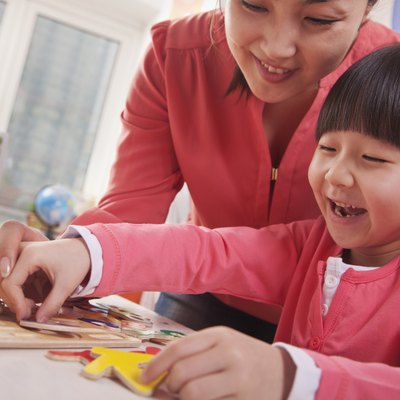 Teacher Helping Young Girl with Cut-Out Alphabet Letters