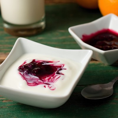 Red berry fruit in white yogurt placed with bowl