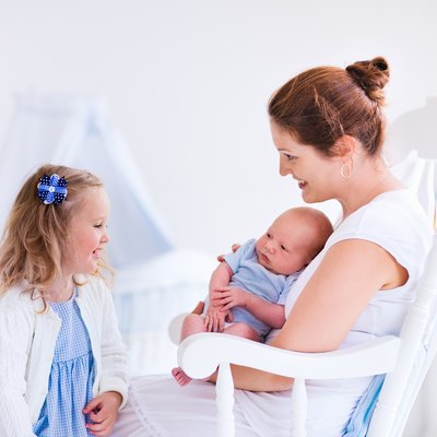 Mother with daughter and baby in a white nursery