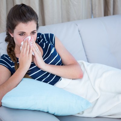 Sick woman blowing her nose on couch