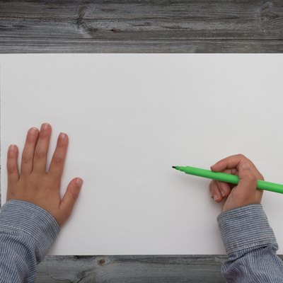 child holding pen over blank sheet of paper. kids hands