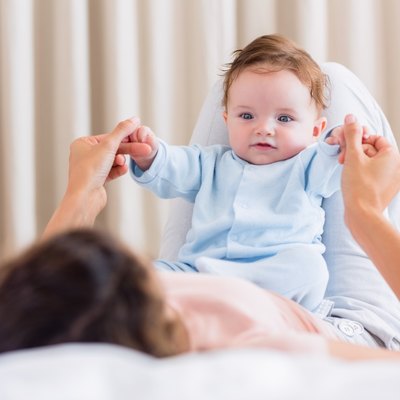 Baby playing with mother in bed