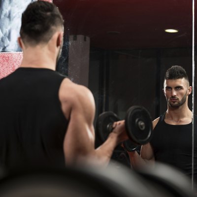 Young Man Lifting Dumbbell In Gym