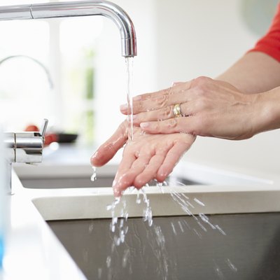 Close Up Of Woman Washing Hands In Kitchen Sink