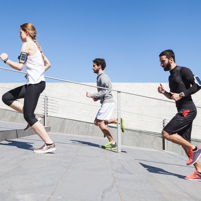 Three young friends running on the steps of a building