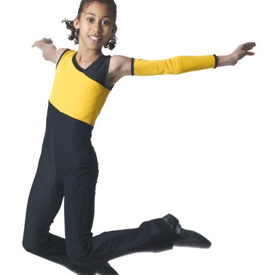 an african american girl in a black and yellow dance outfit jumps through the air