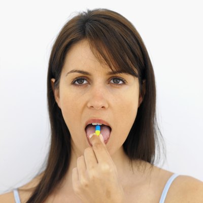 Front view portrait of young woman putting tablet in her mouth