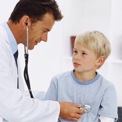 Side profile of a male doctor checking a young boy's (8-10) chest with a stethoscope