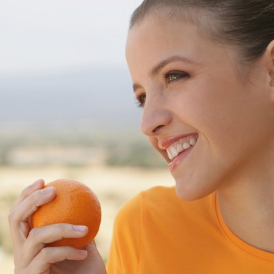 Young woman smiling with orange in her hand