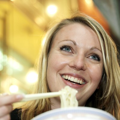 Woman eating noodles, smiling, low angle view