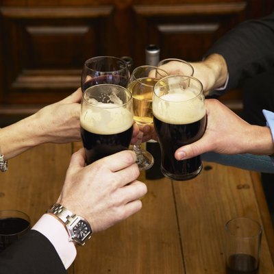 Five colleagues toasting each other with drinks in bar, close-up