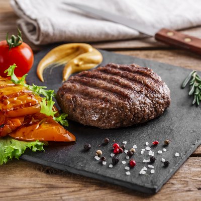 burger grill with vegetables and sauce on a wooden surface