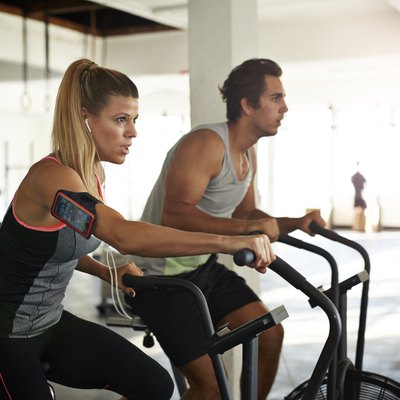 Woman & man working out on crosscycle at gym