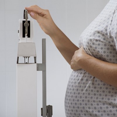 Pregnant woman weighing herself on hospital scale
