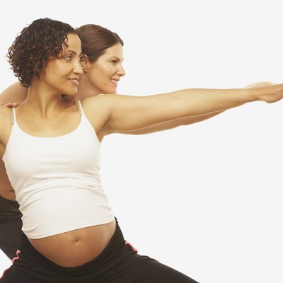 Yoga trainer assisting pregnant woman