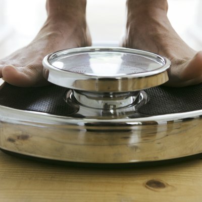 Man standing on weight scale, close-up, low section