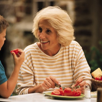 Grandmother with grandson while cutting tomatoes