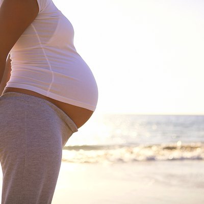 Torso of pregnant woman on beach