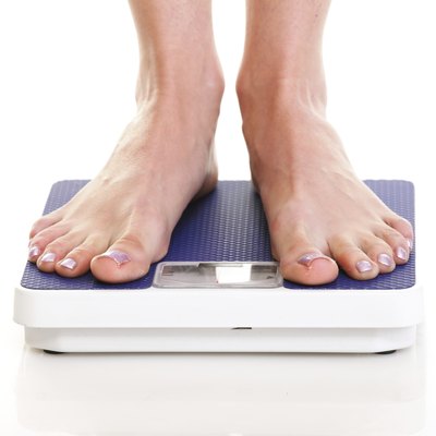Woman feet and weight scale isolated on white background