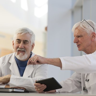 Two doctors discussing information on a computer and a tablet