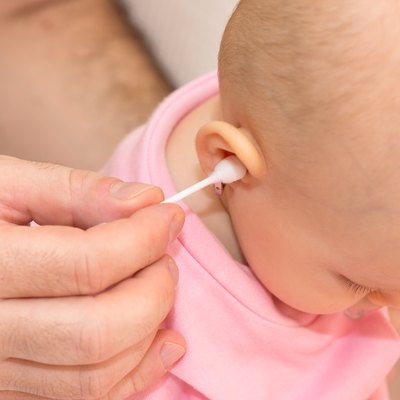 Father cleaning baby's ear