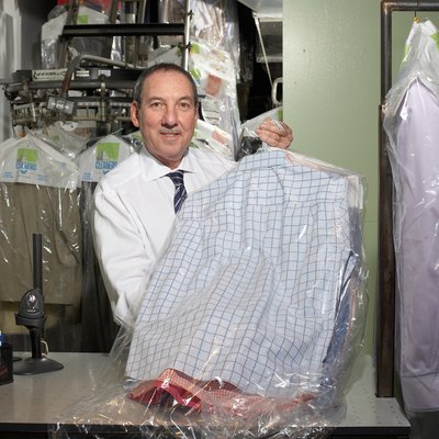 Dry cleaners operator holding shirts on hangers, portrait