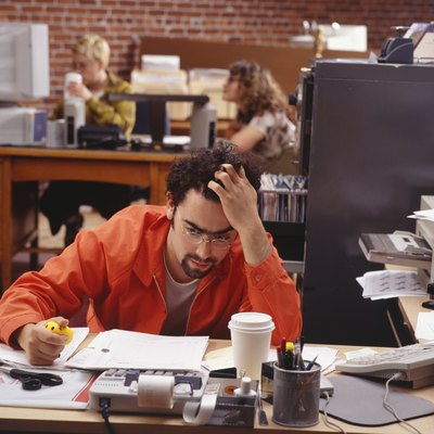 Man sitting at desk, supporting head with hand