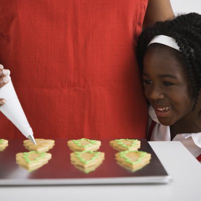 African girl watching mother decorate cookies
