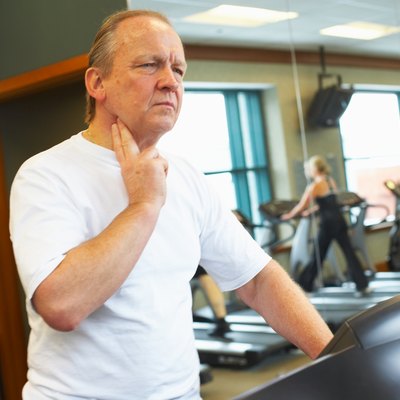 Man checking his pulse on treadmill at gym