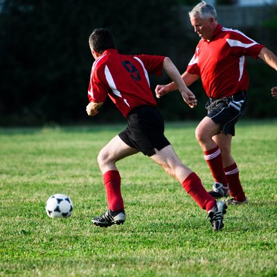 Soccer players chasing ball in game