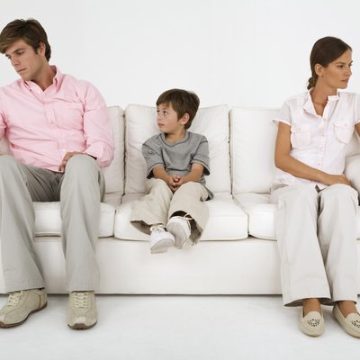 Boy sitting on couch with aloof parents