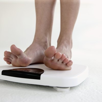 Young woman standing on scale, low section, close-up