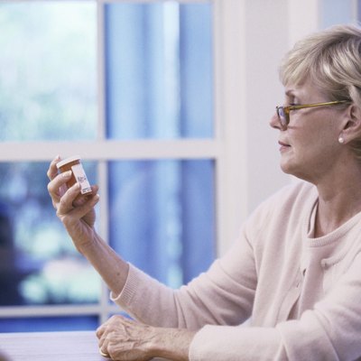 Senior woman reading the label on a pill bottle