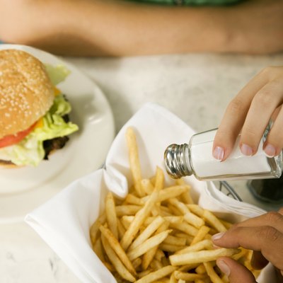 Close up of a girl putting salt on her fries